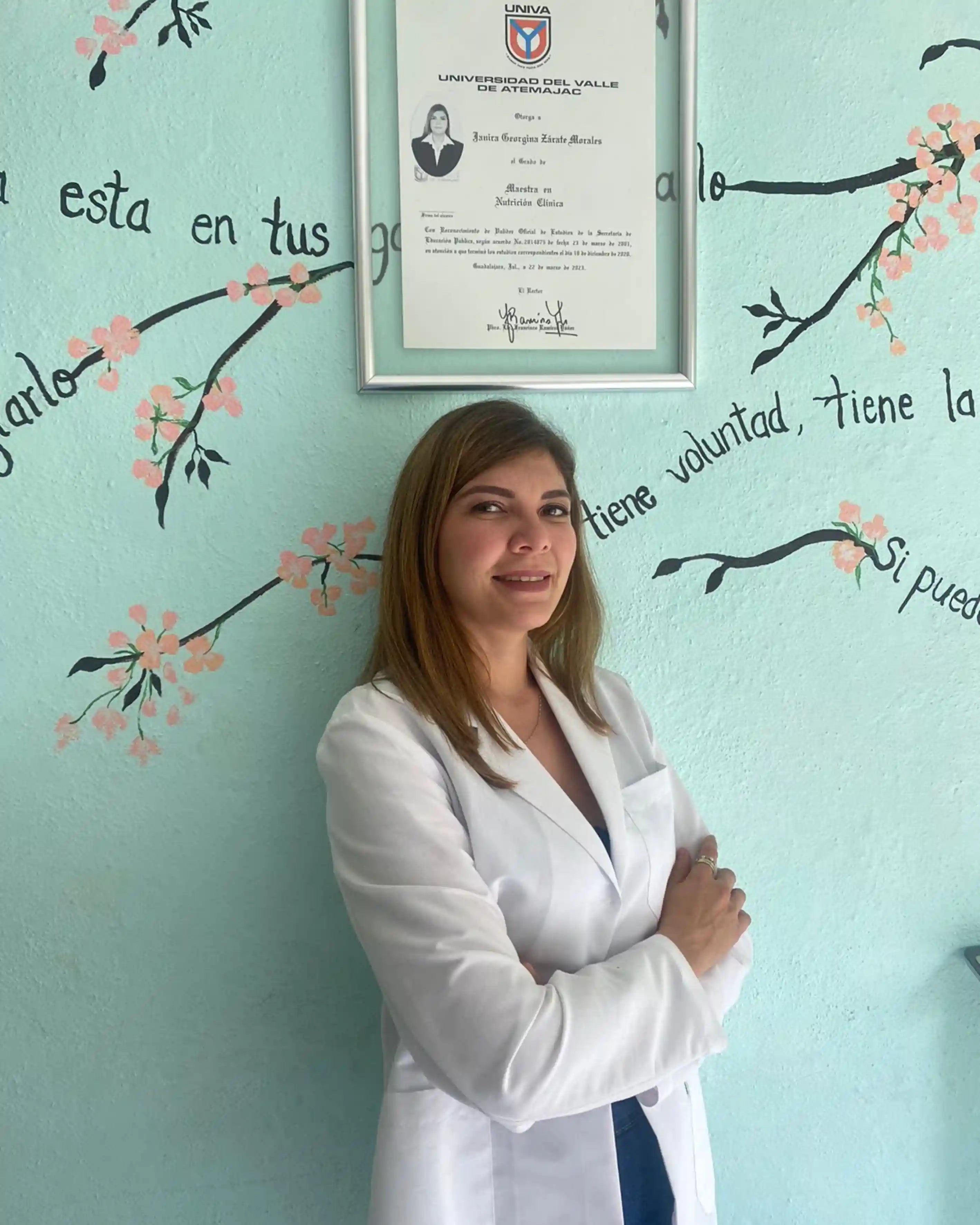 Nutrióloga Jani Zárate de pie frente a mural de bienestar en consultorio HBH
